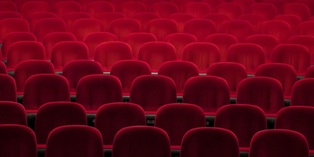 The empty red plush seats of a stage or cinema.